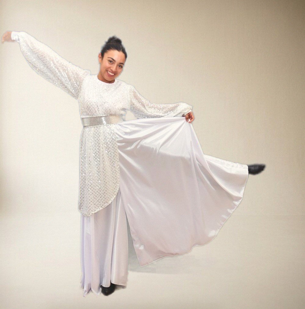 Bailarina con vestido blanco de tul con lentejuelas, con una pierna levantada, sobre fondo azul